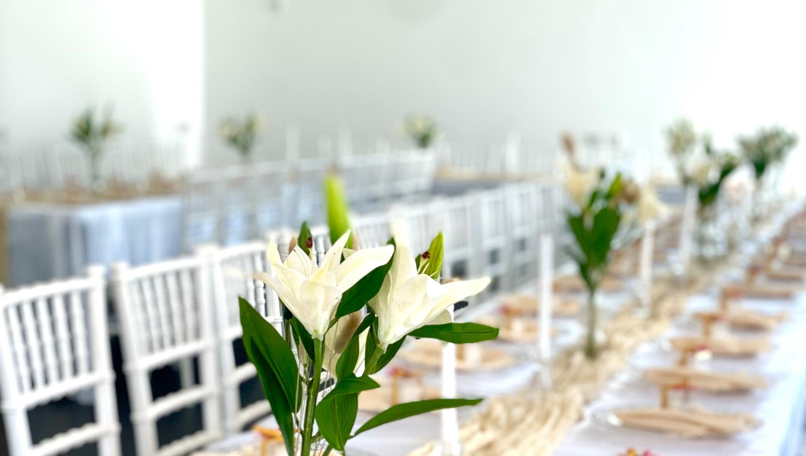 Eleganter Veranstaltungsraum mit weißen Stühlen und festlich gedeckten Tischen